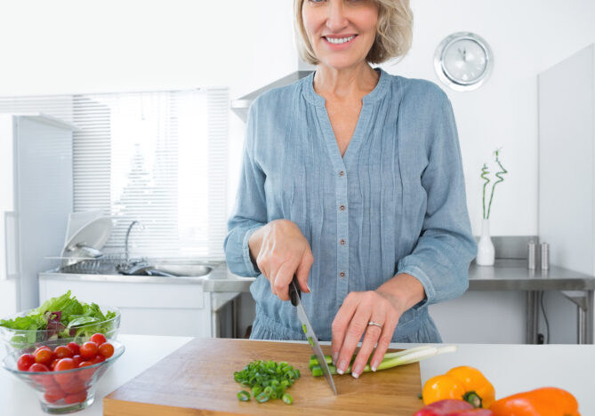 Happy woman chopping vegetables