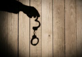 Male Hand with Handcuffs on Natural Wood Background. You can see more silhouettes and shadows on my page.