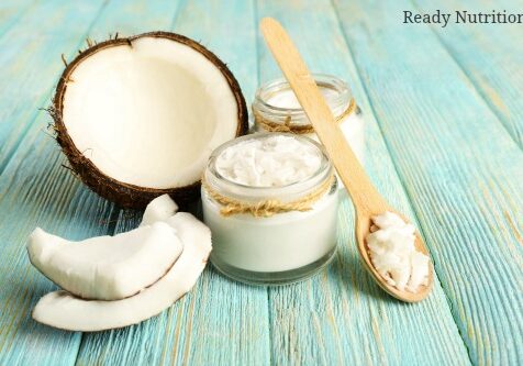 Fresh coconut oil in glassware and wooden spoon on color wooden table background