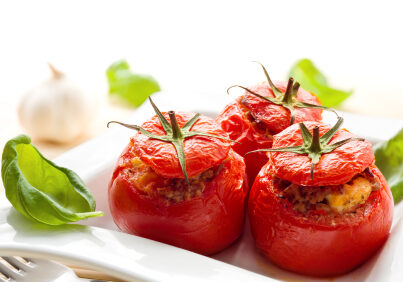 Three stuffed tomatoes on a white plate.