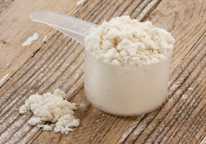 a scoop of whey protein isolate powder on a grunge wooden table background