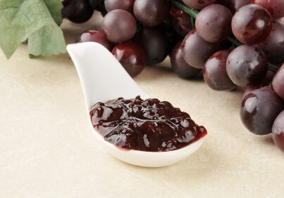 A spoonful of grape jam with fresh grapes