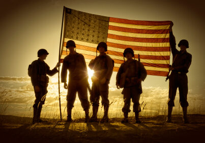 Four WWII Soldiers Holding up a translucent American Flag at sundown.  The sun  behind the flag creates a semi-silhouette of the four war weary soldiers.  Clouds, sun, and sand complete the picture.  All soldiers are in uniform with helmets and rifles, boots etc.