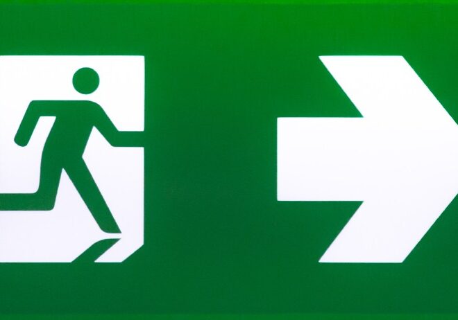 green emergency exit sign showing the way to escape