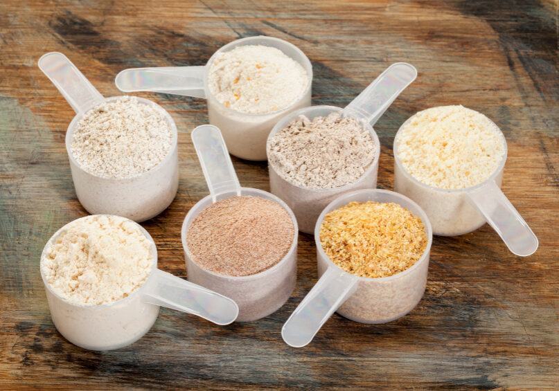 measuring scoops of gluten free flours - almond, coconut, teff, flaxseed meal, whole rice, brown rice, buckwheat